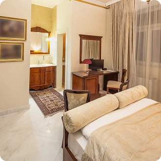 Elegante camera d'hotel con letto matrimoniale, scrivania in legno, pavimento in marmo e un'area vanità aperta, progettata per un soggiorno confortevole.