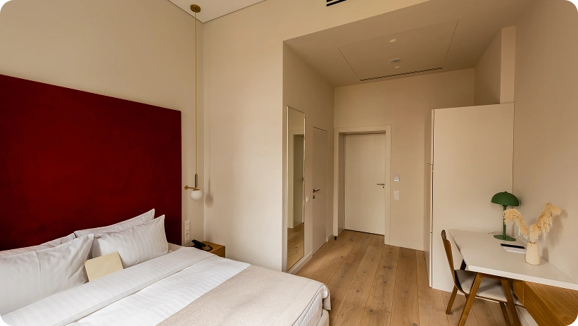 Camera d'hotel contemporanea con testiera rossa audace, spazio di lavoro minimalista e design d'interni moderno e luminoso.