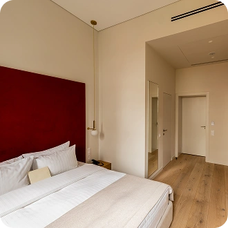 Camera d'hotel contemporanea con testiera rossa audace, spazio di lavoro minimalista e design d'interni moderno e luminoso.